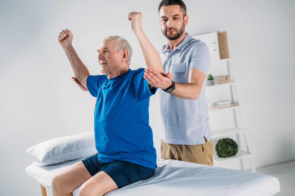 portrait of focused physiotherapist doing massage to senior man on massage table