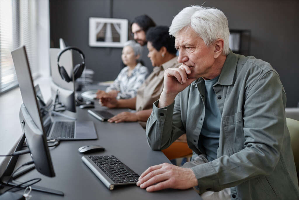Side view portrait of confused senior man using computer