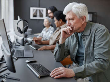 Side view portrait of confused senior man using computer