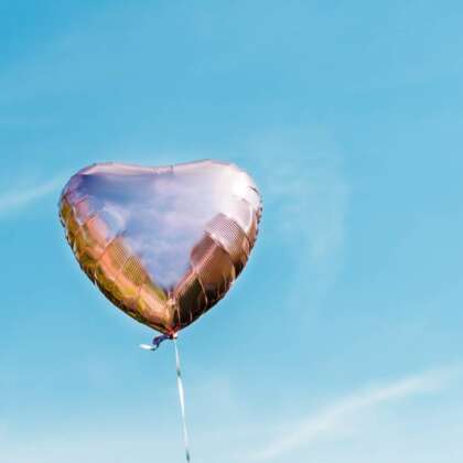 Heart shaped metallic balloon on a blue sky background