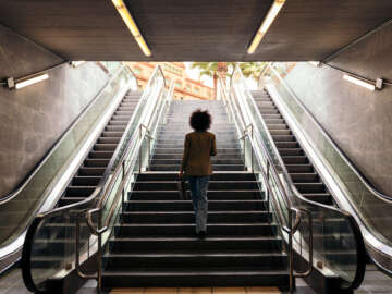 rear view of the silhouette of an unrecognizable business woman walking up the stairs of the subway station with a briefcase in her hand, concept of urban lifestyle and growth Part of an article on stealing fitness, taking small steps in everyday life to get fit without a large impact.