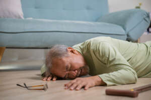 Elderly / older man who has fallen on the floor alone with walking stick preventing falls