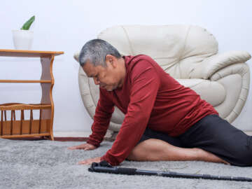Elderly / older man who has fallen on the floor alone with walking stick preventing falls
