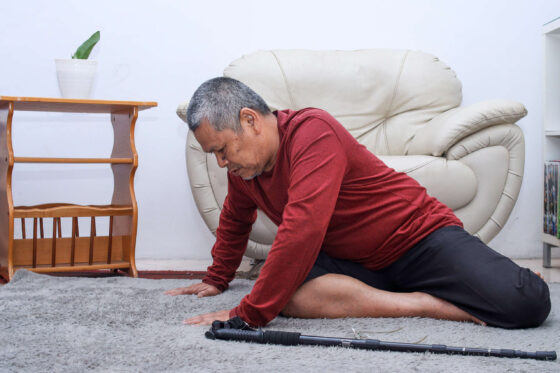 Elderly / older man who has fallen on the floor alone with walking stick preventing falls