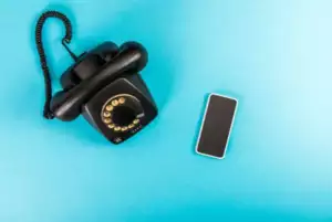 A 1960s telephone next to a modern smartphone on a blue background