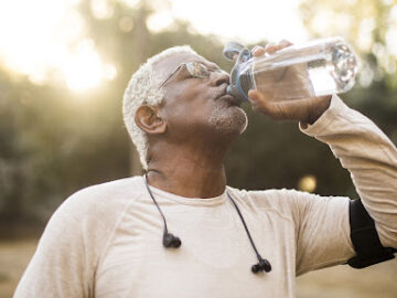 older man drinking water outdoors after exercising. Black man middle aged. Brighton and Hove physiotherapy